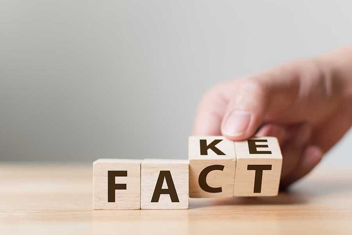 A group of four wooden cubes with letters spelling FACT and FAKE