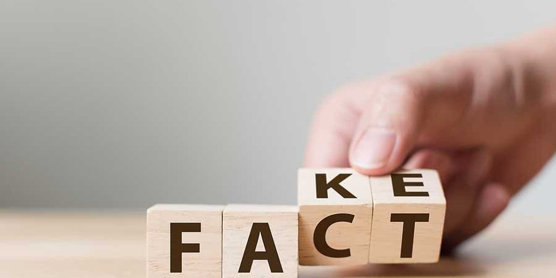 A group of four wooden cubes with letters spelling FACT and FAKE
