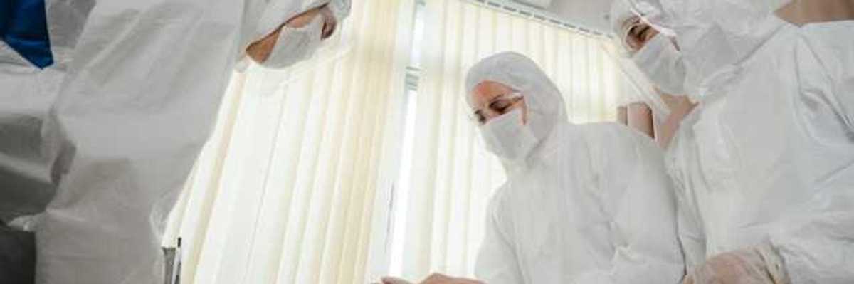 A group of masked health professionals standing over a patient's bed
