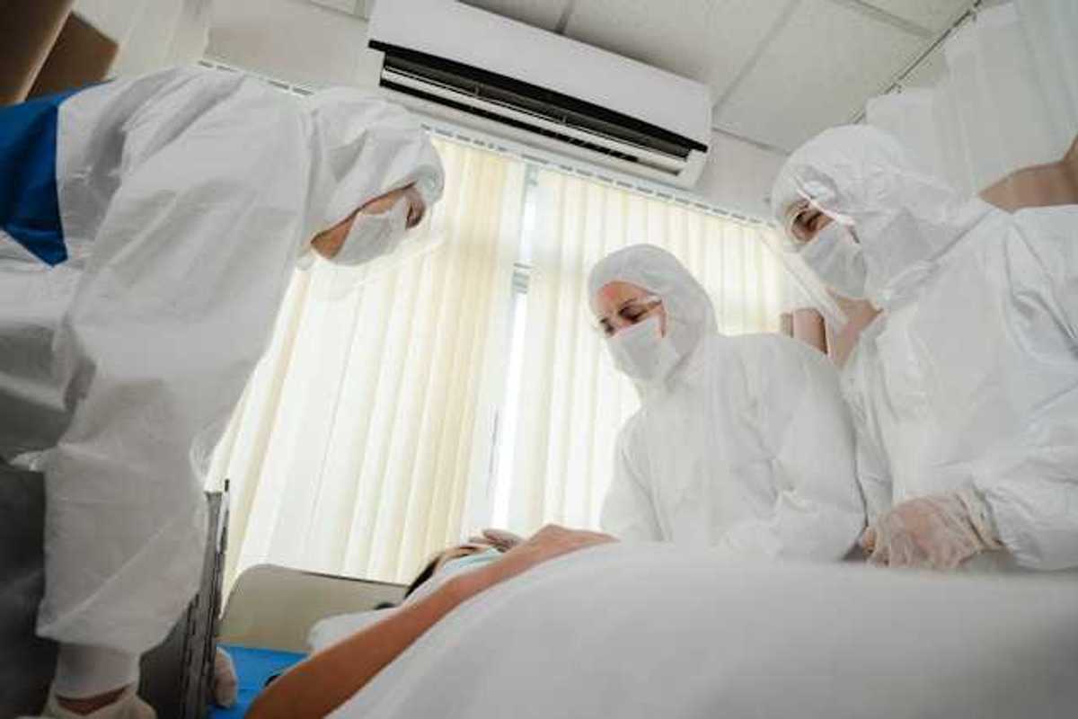 A group of masked health professionals standing over a patient's bed
