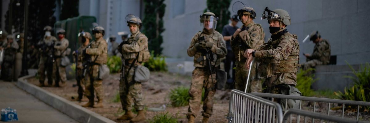 a group of national guard on a sidewalk in front of a building.