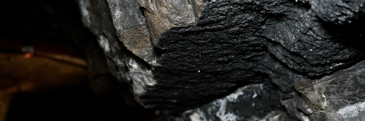 a group of people in yellow hard hats standing in a coal mine.