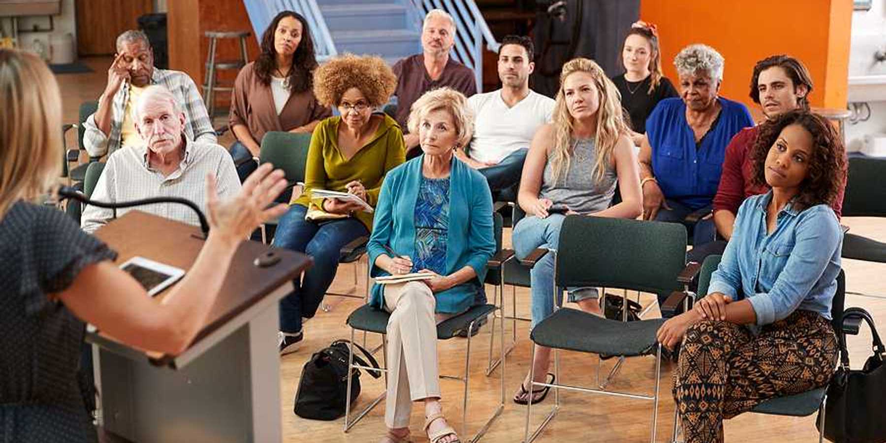 A group of people listening to a speaker at a community neeting