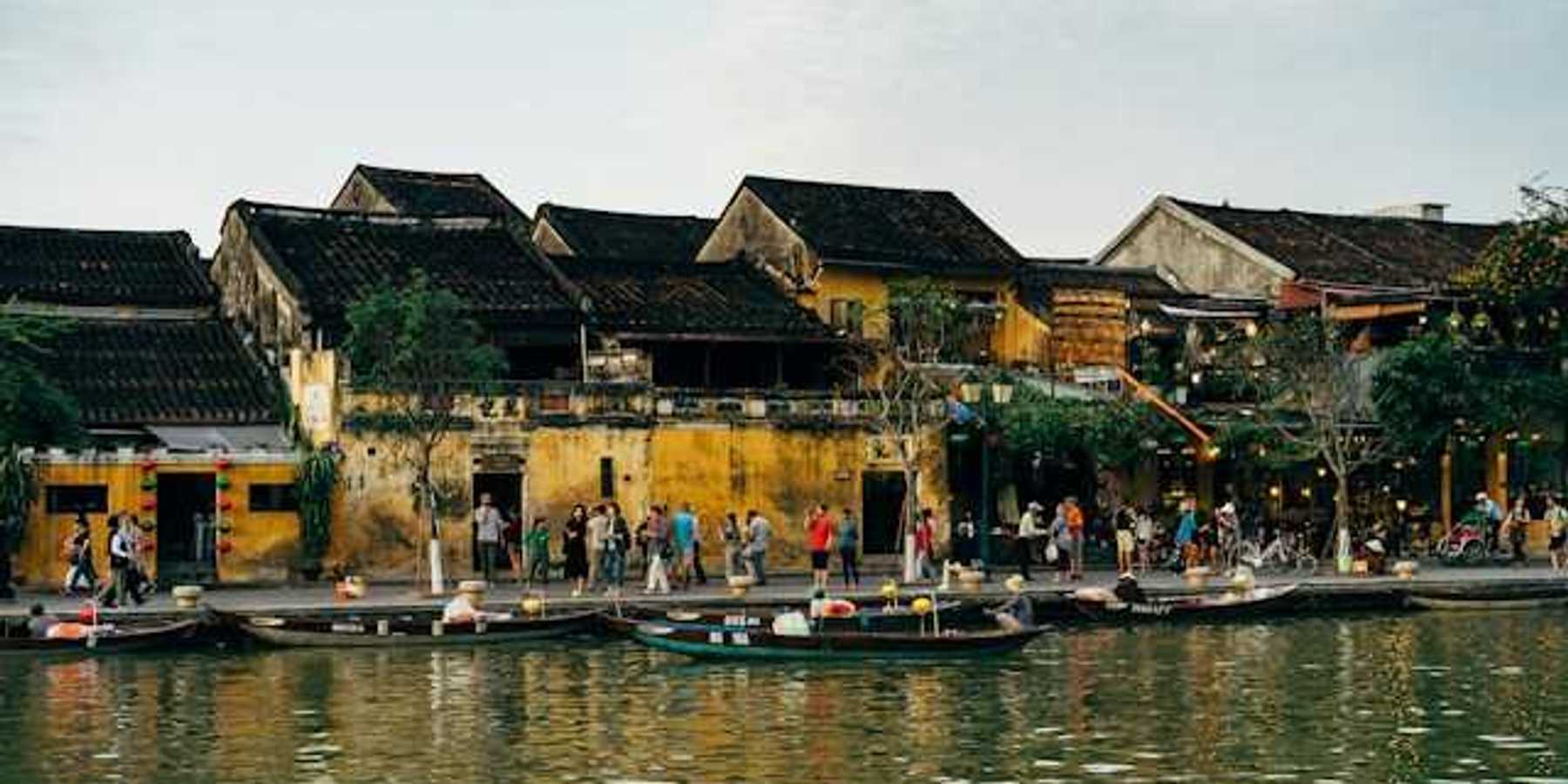 A group of people on a pier standing next to a body of water with small boats