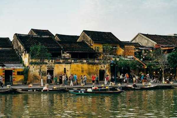 A group of people on a pier standing next to a body of water with small boats