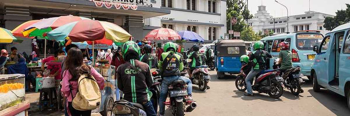 A group of people on motorbikes outside a Jakarta train station
