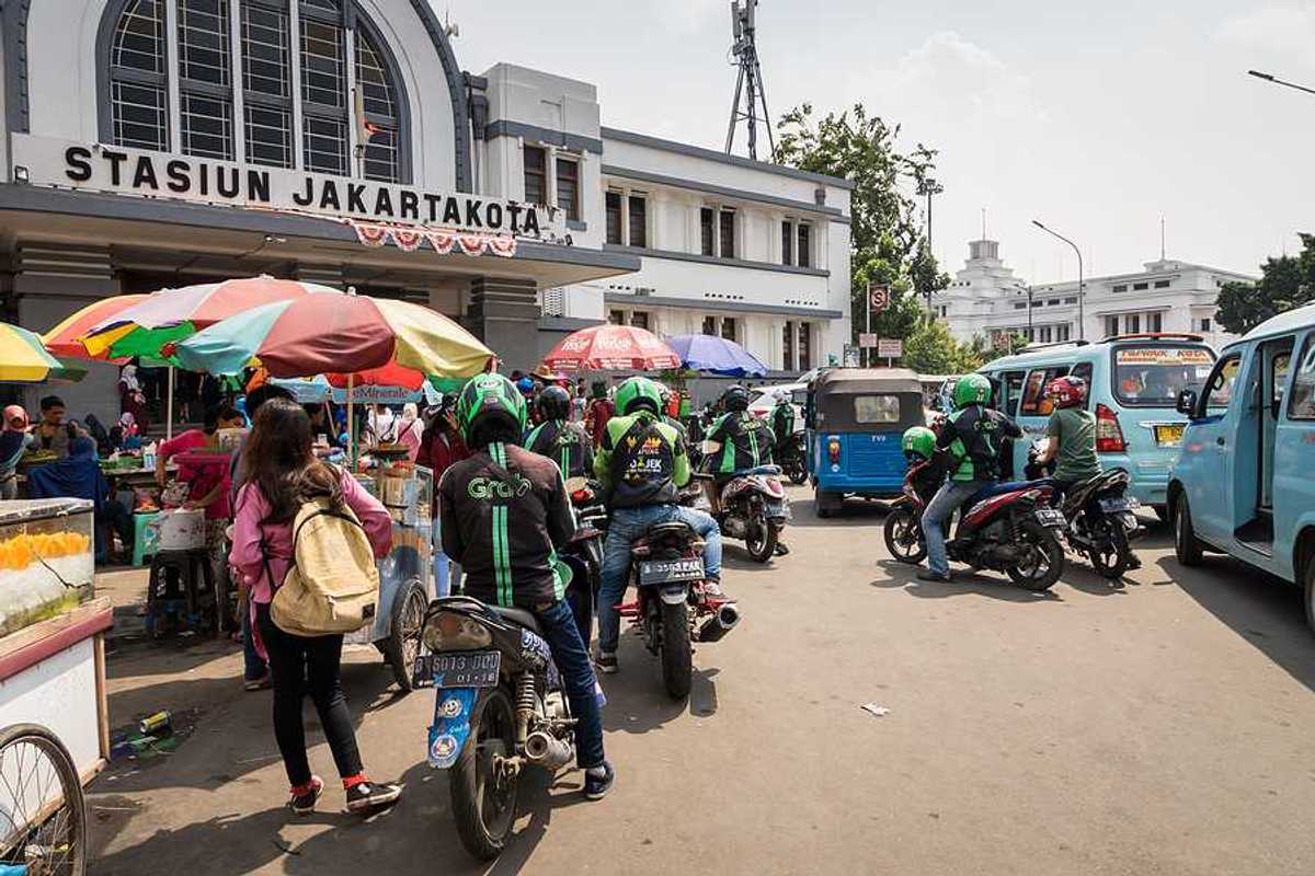 A group of people on motorbikes outside a Jakarta train station