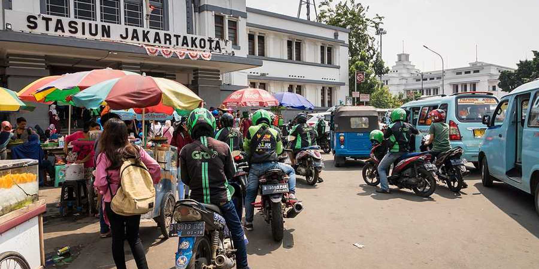 A group of people on motorbikes outside a Jakarta train station