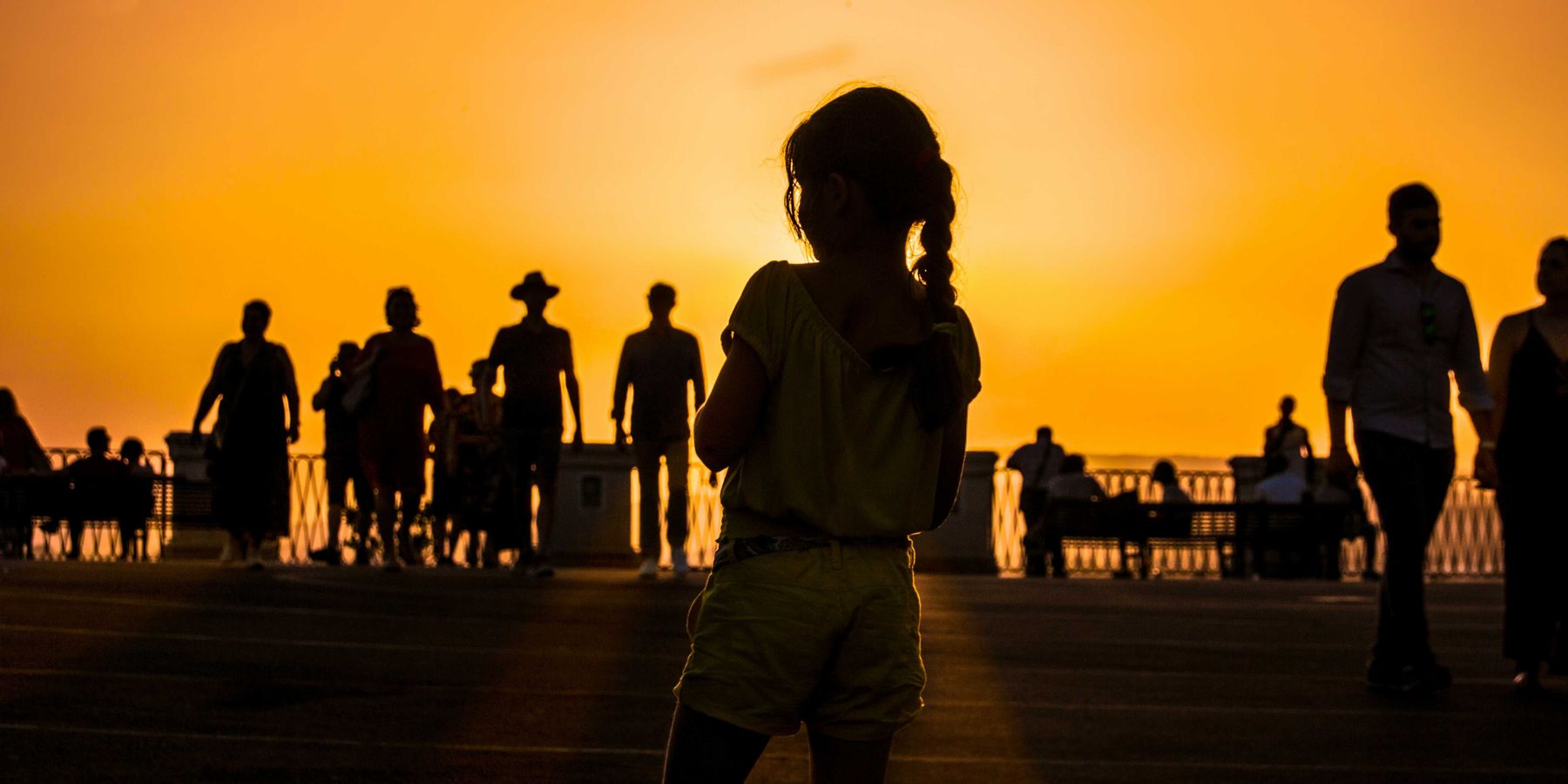 A group of people silhouetted against an orange sun-tinged sky