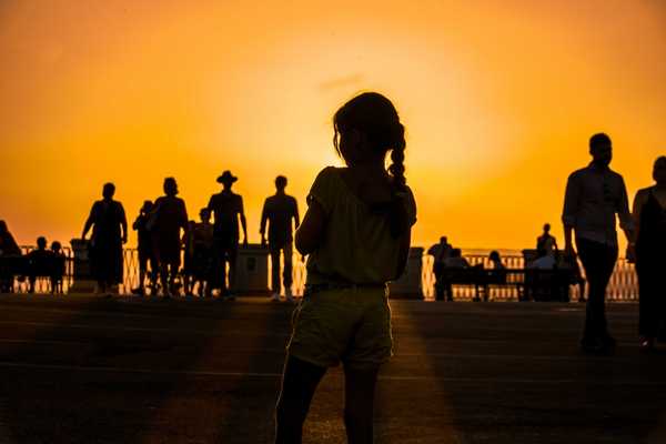 A group of people silhouetted against an orange sun-tinged sky