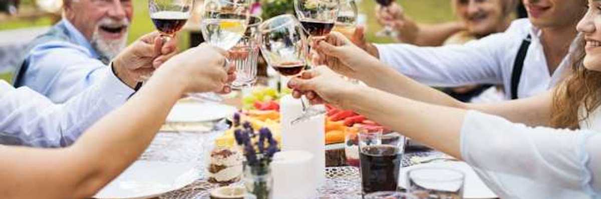 A group of people sitting at an outside table holding glasses of wine