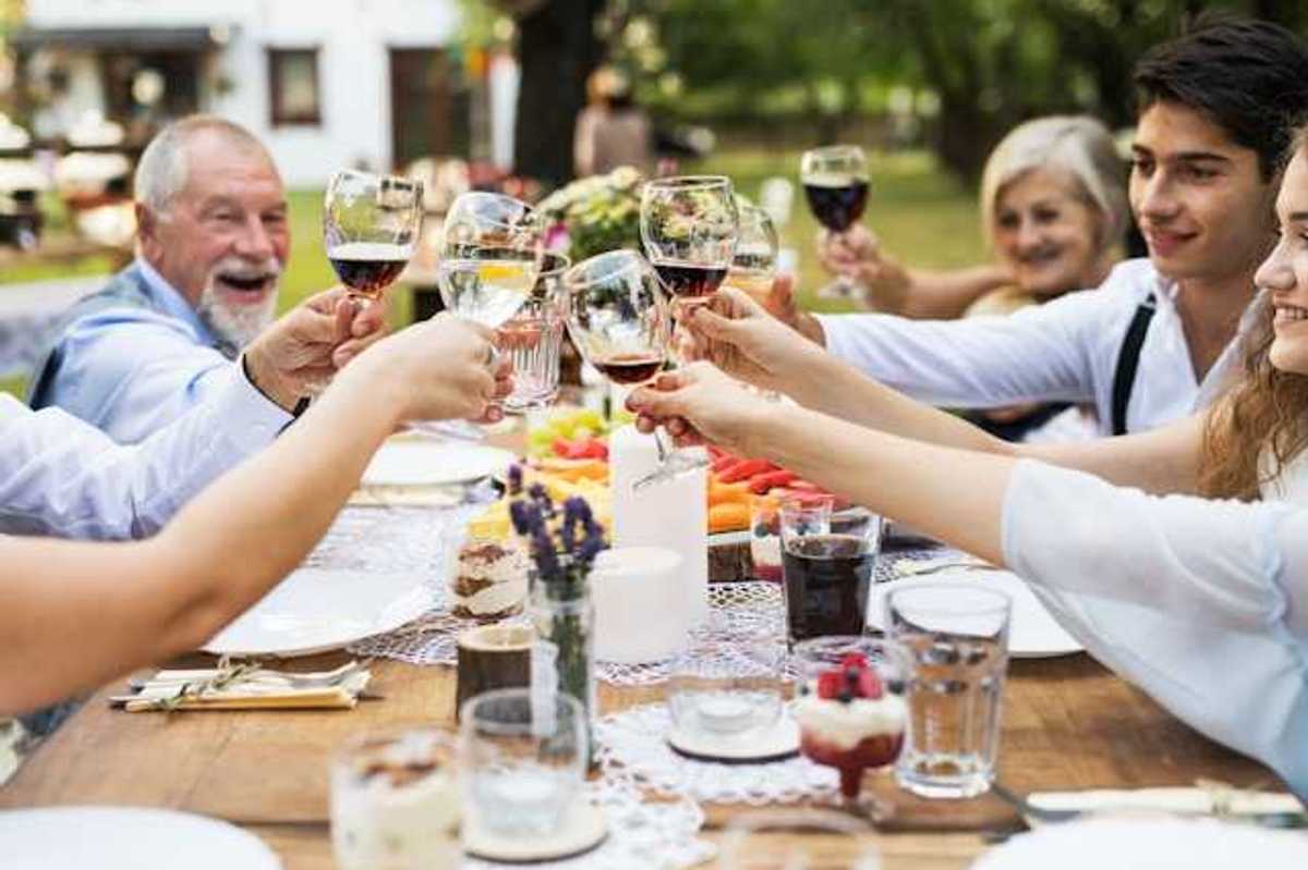 A group of people sitting at an outside table holding glasses of wine
