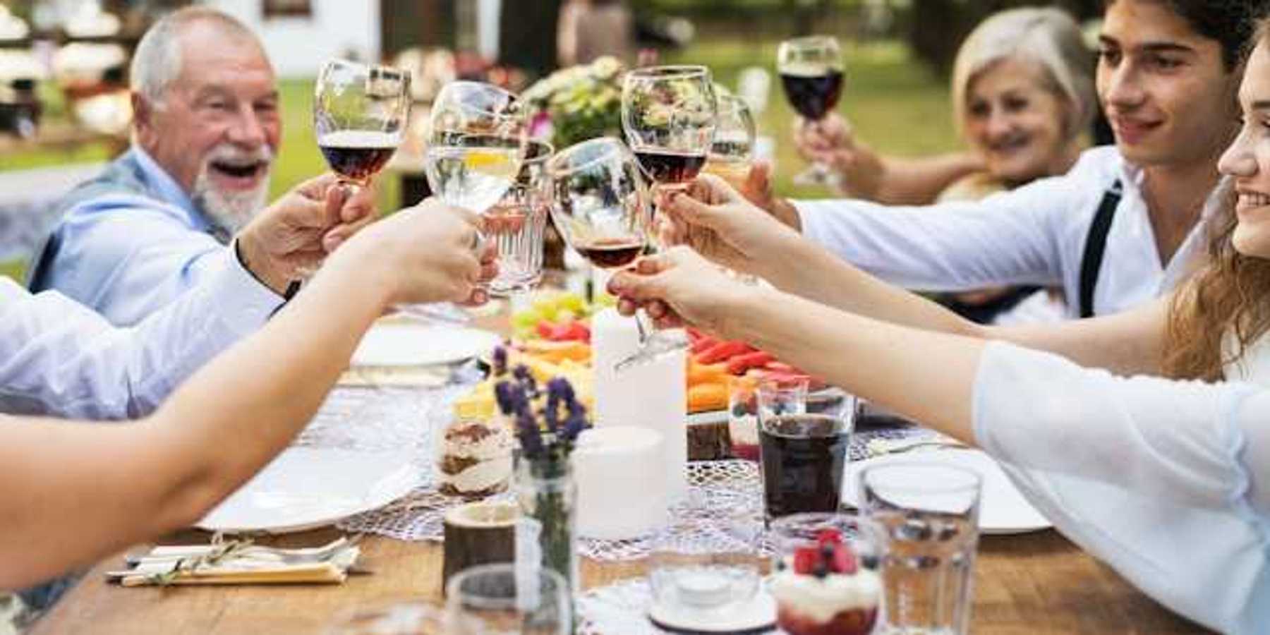 A group of people sitting at an outside table holding glasses of wine