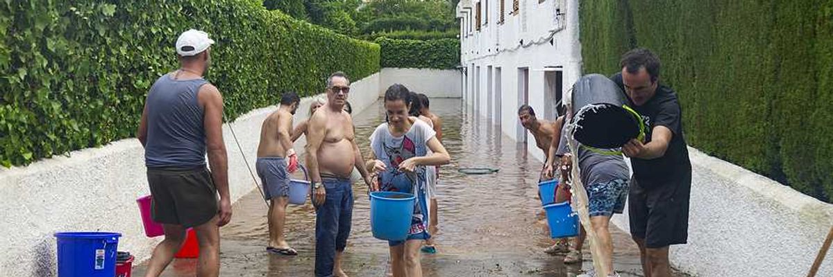 A group of people with buckets trying to carry water from a flooded apartment building