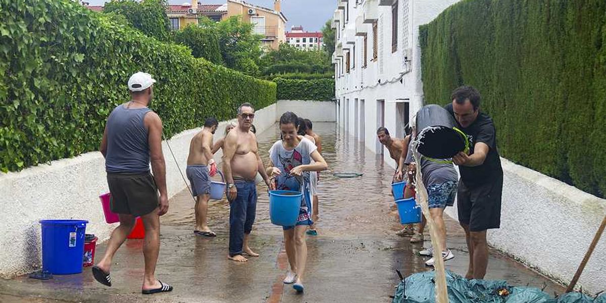 A group of people with buckets trying to carry water from a flooded apartment building