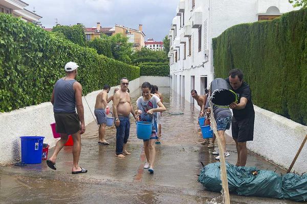A group of people with buckets trying to carry water from a flooded apartment building