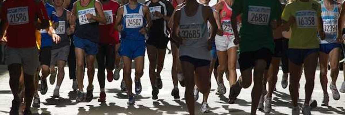 A group of runners with numbered tags running on a city street