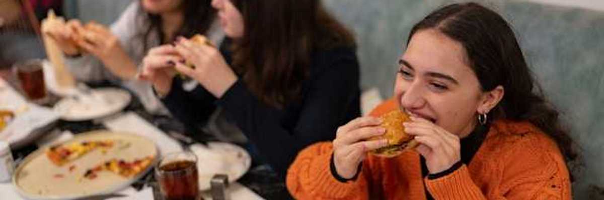 A group of teenage girls eating burgers and pizza