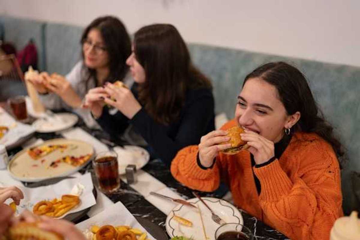 A group of teenage girls eating burgers and pizza
