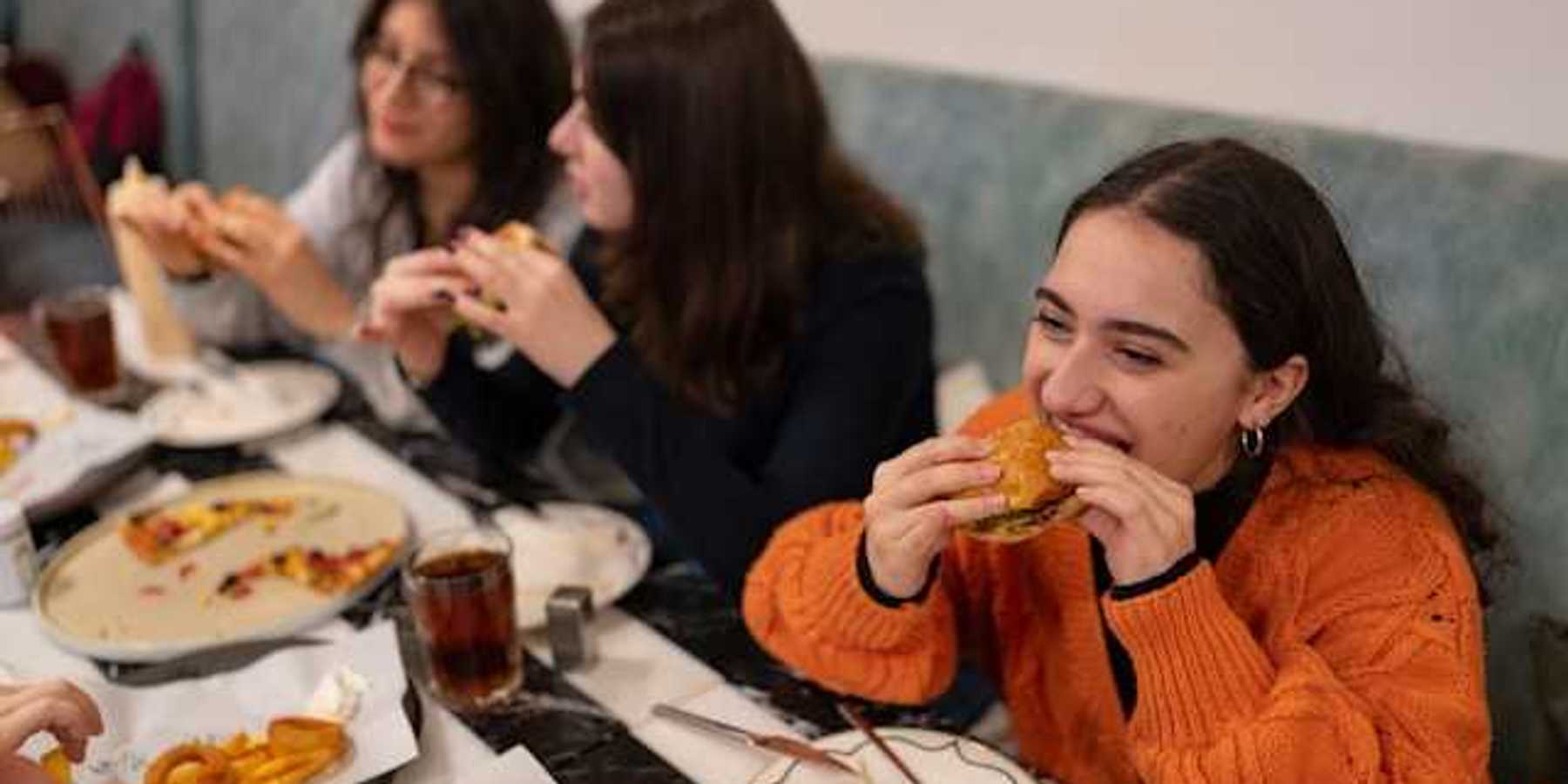 A group of teenage girls eating burgers and pizza