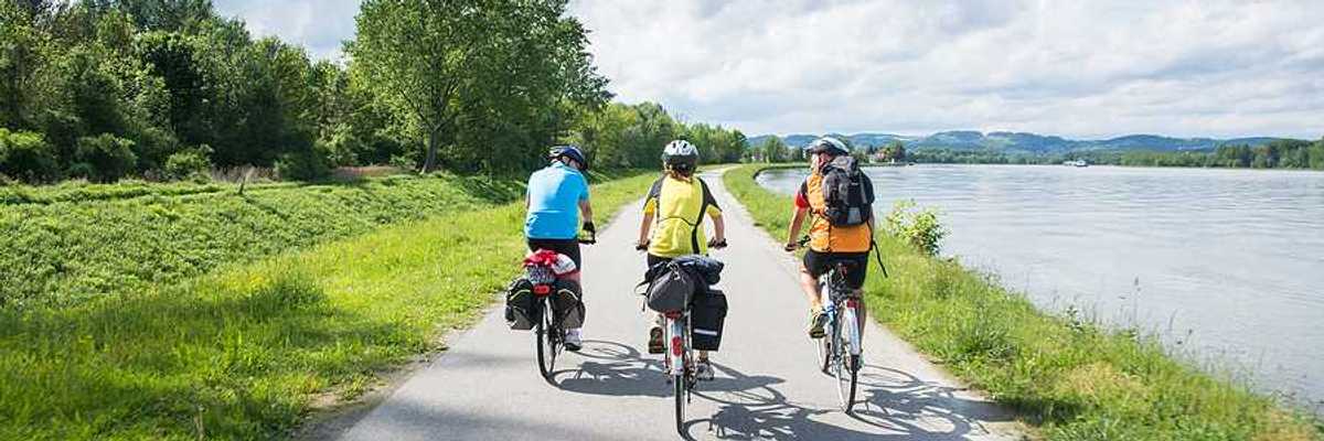 A group of three cyclists bicycling alongside a river