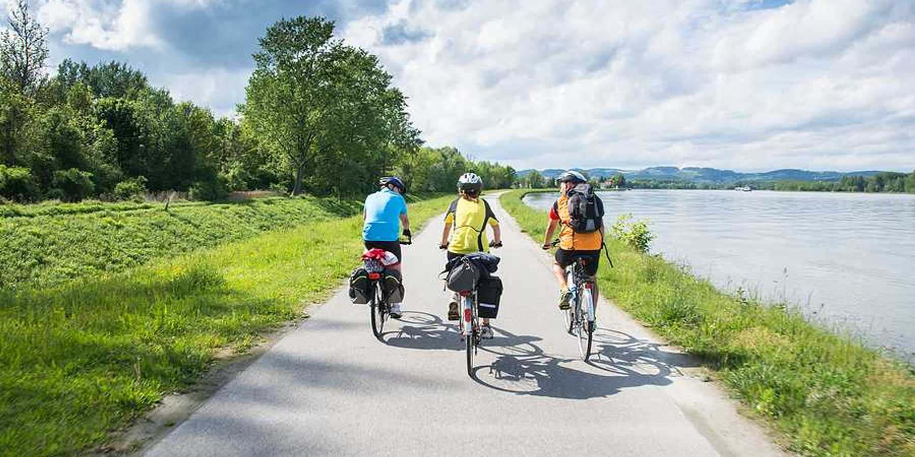 A group of three cyclists bicycling alongside a river