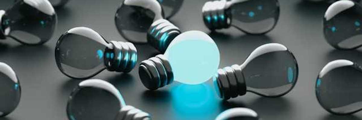 A group of unlit lightbulbs with one bulb glowing blue