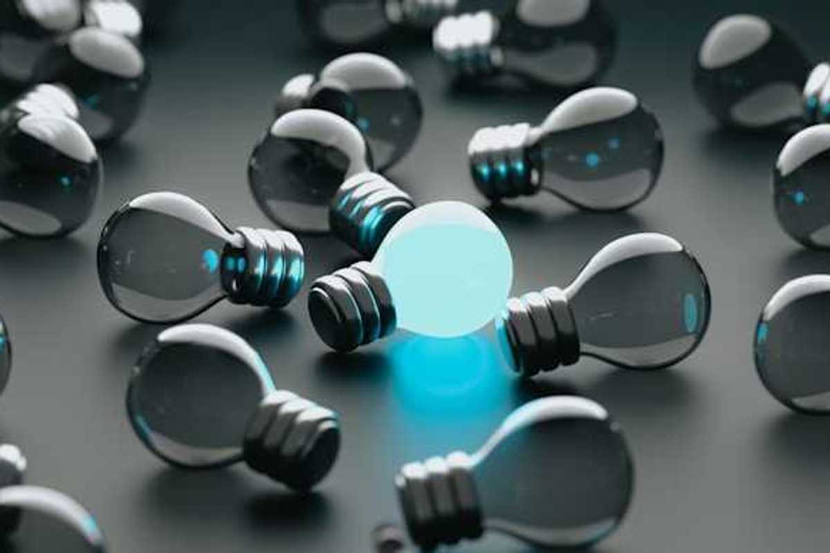 A group of unlit lightbulbs with one bulb glowing blue