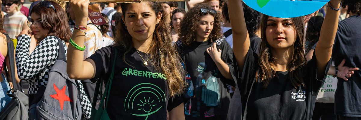 a group of young people holding up climate protest signs in the street.