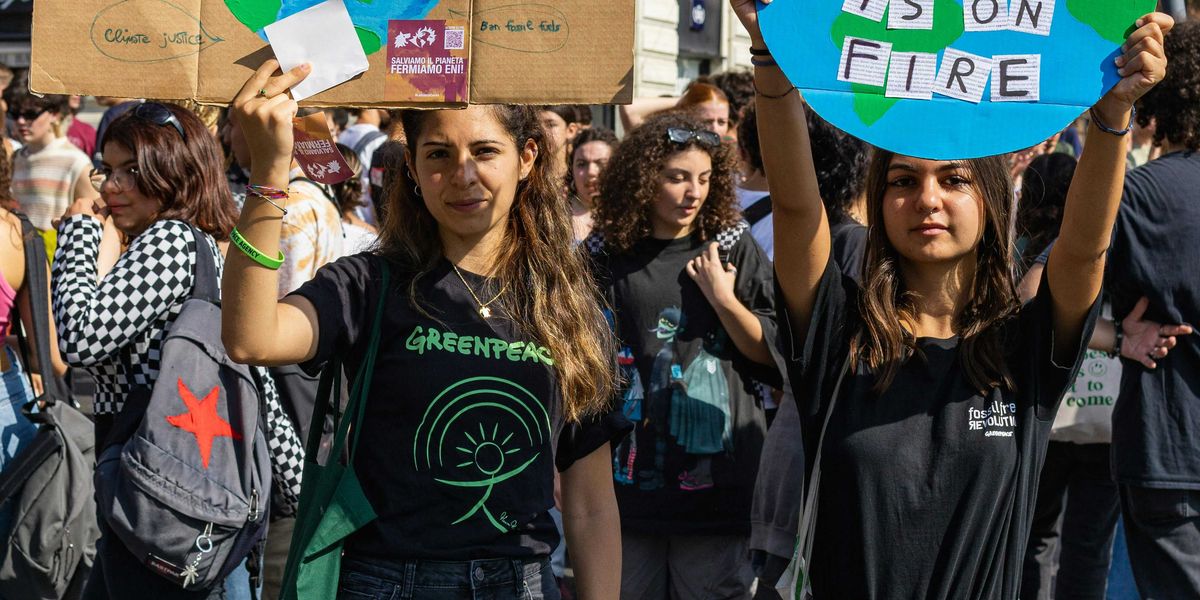 a group of young people holding up climate protest signs in the street.