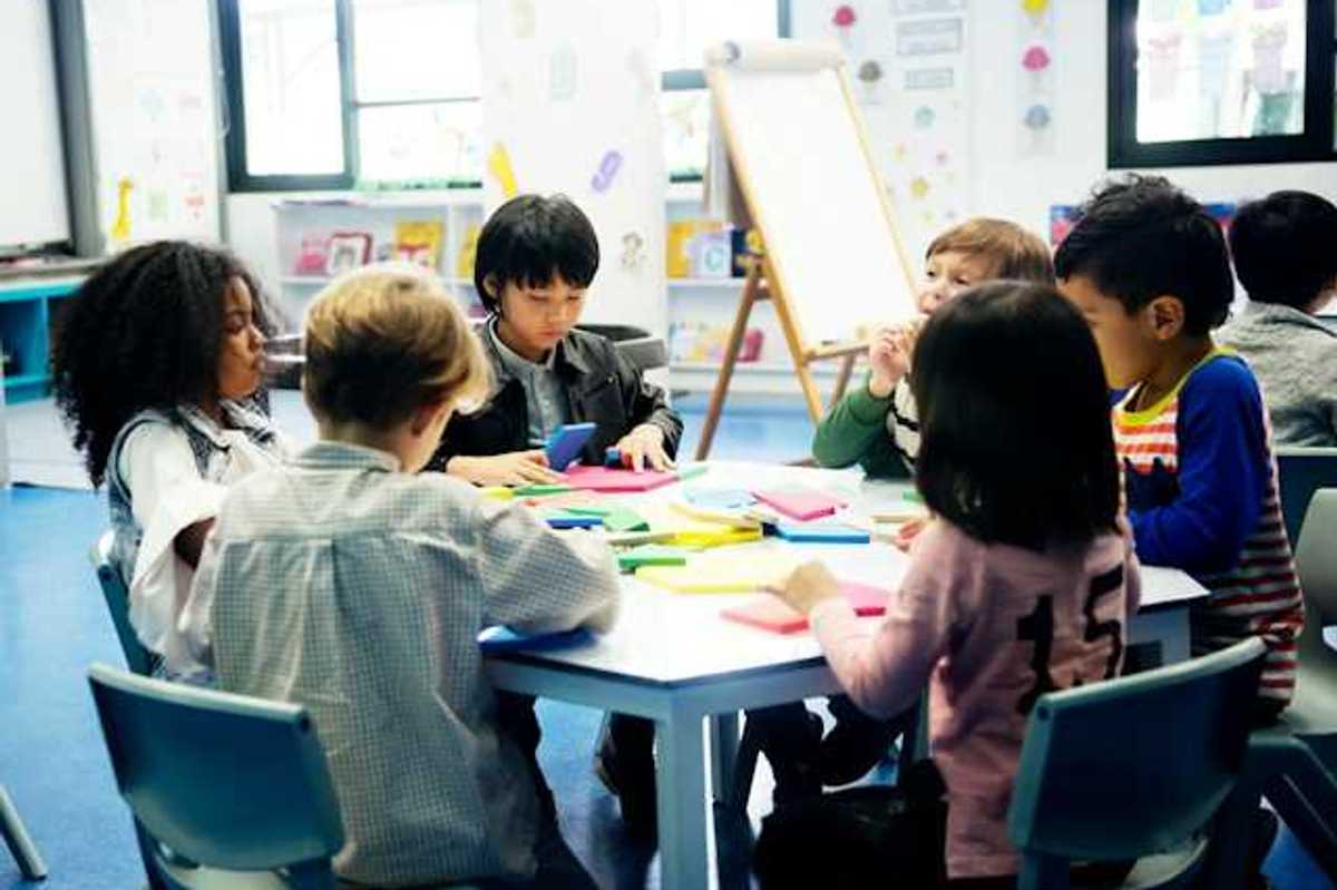 A group of young school children sitting around a table