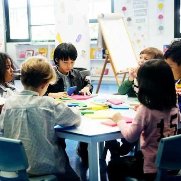 A group of young school children sitting around a table