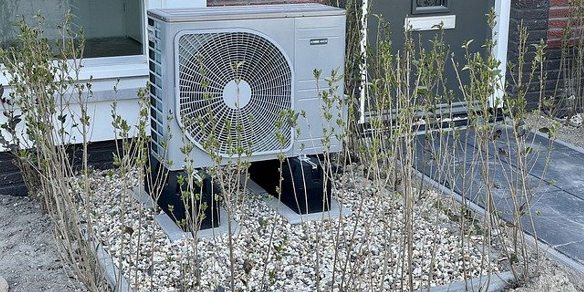 A heat pump installed outside of a brick building.
