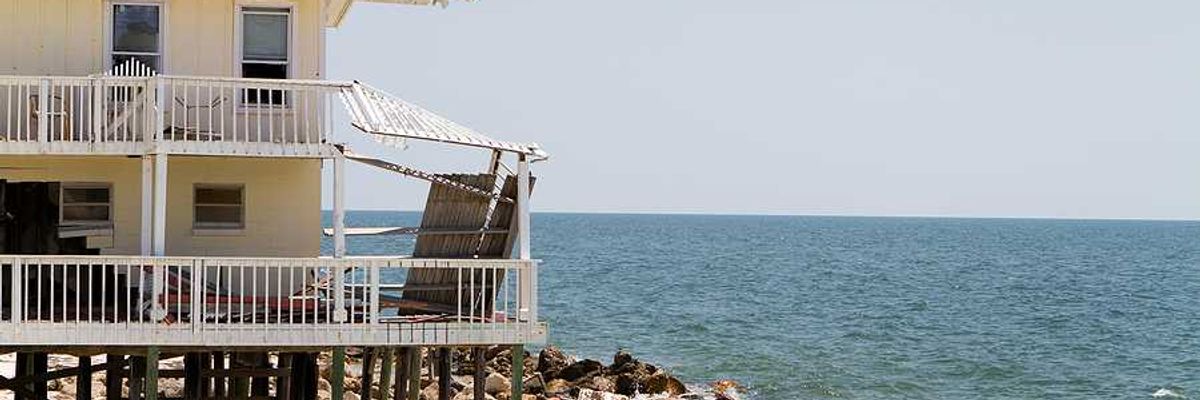 A home on stilts on the edge of an encroaching ocean