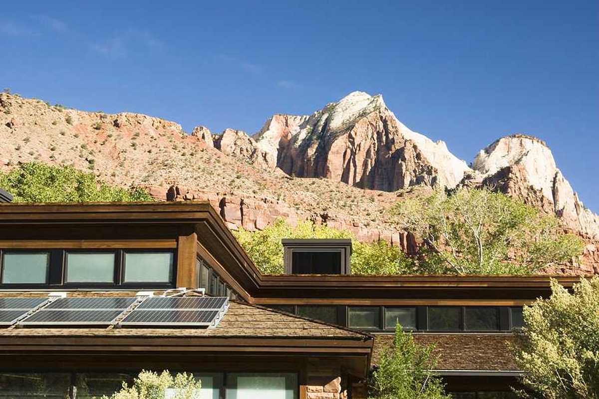 A house with solar panels on the roof with dry hills in the background