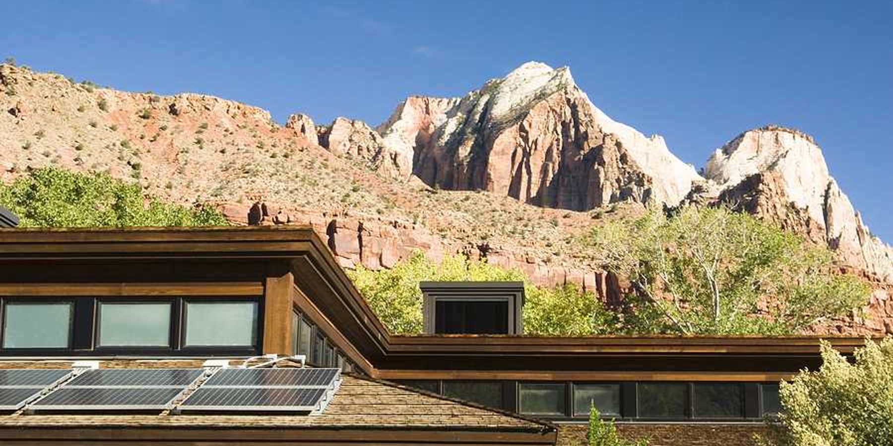 A house with solar panels on the roof with dry hills in the background