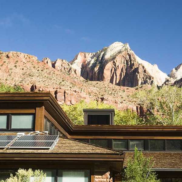A house with solar panels on the roof with dry hills in the background