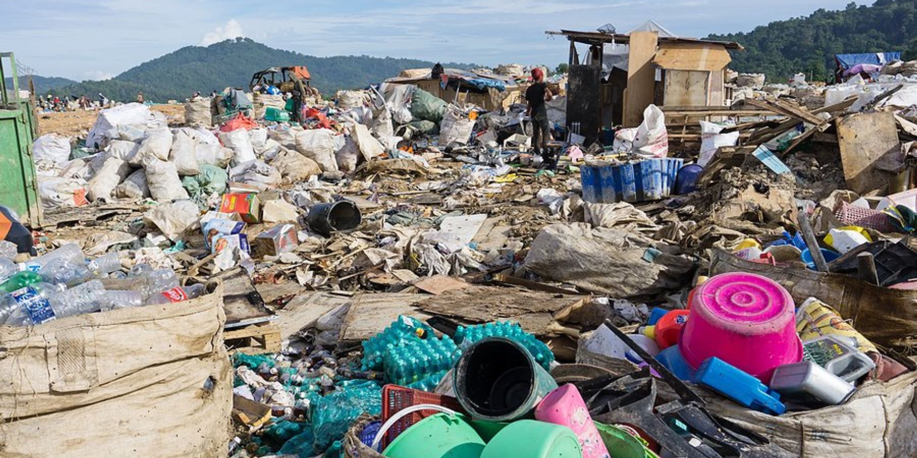 A landfill with piles of plastic waste being collected.