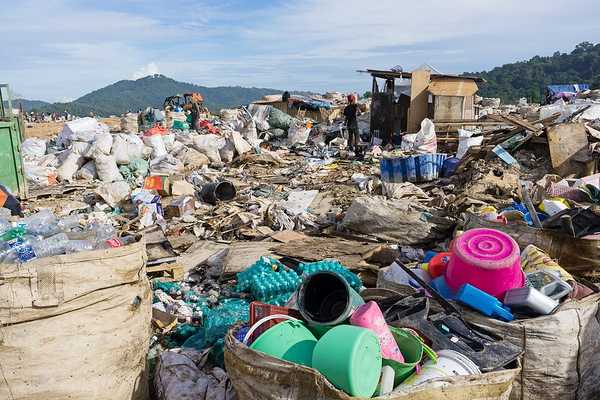 A landfill with piles of plastic waste being collected.