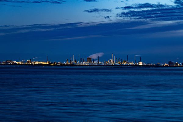 A large body of water with a refinery complex in the background.