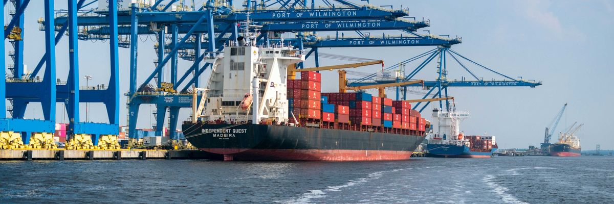 a large cargo ship in the water with a large crane in the background.