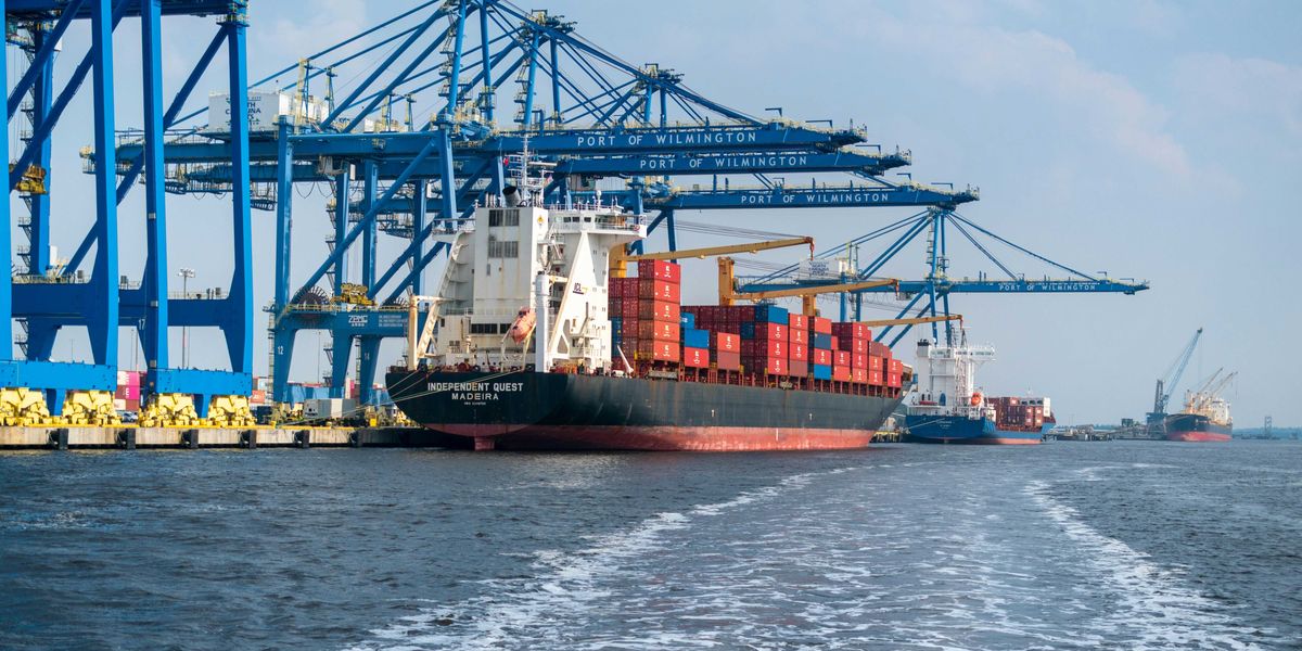 a large cargo ship in the water with a large crane in the background.