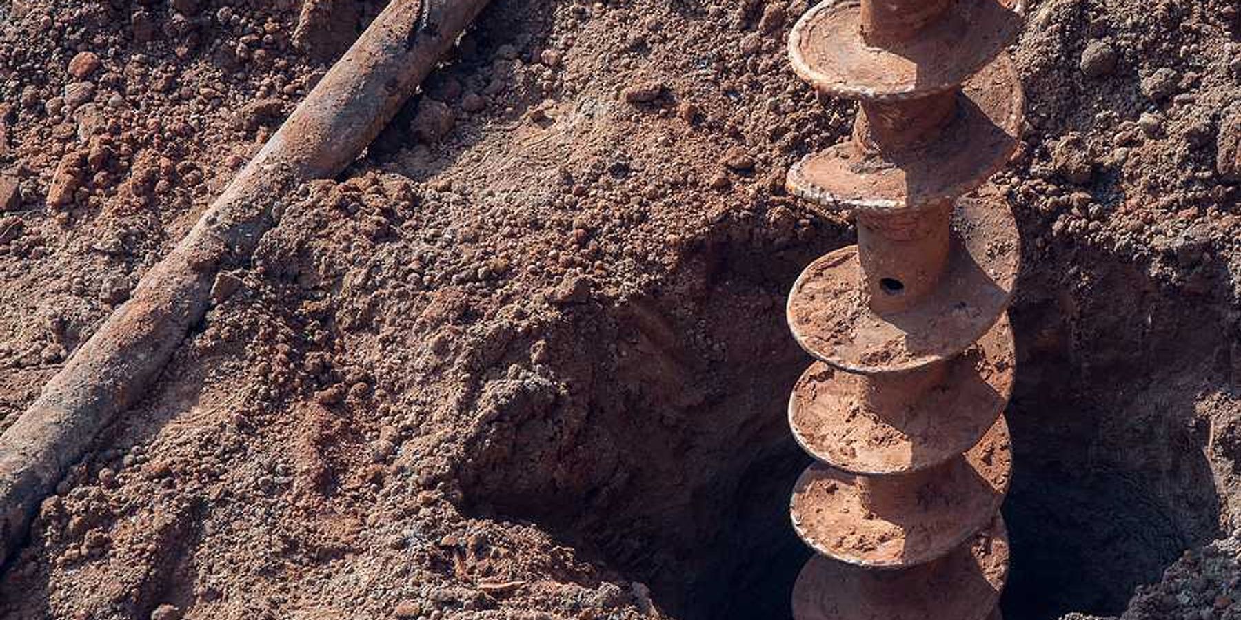 A large drill making a hole in dry earth