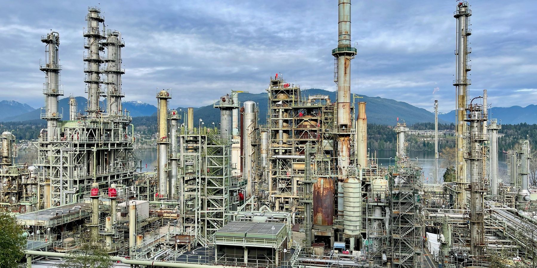 A large oil refinery with mountains in the background.