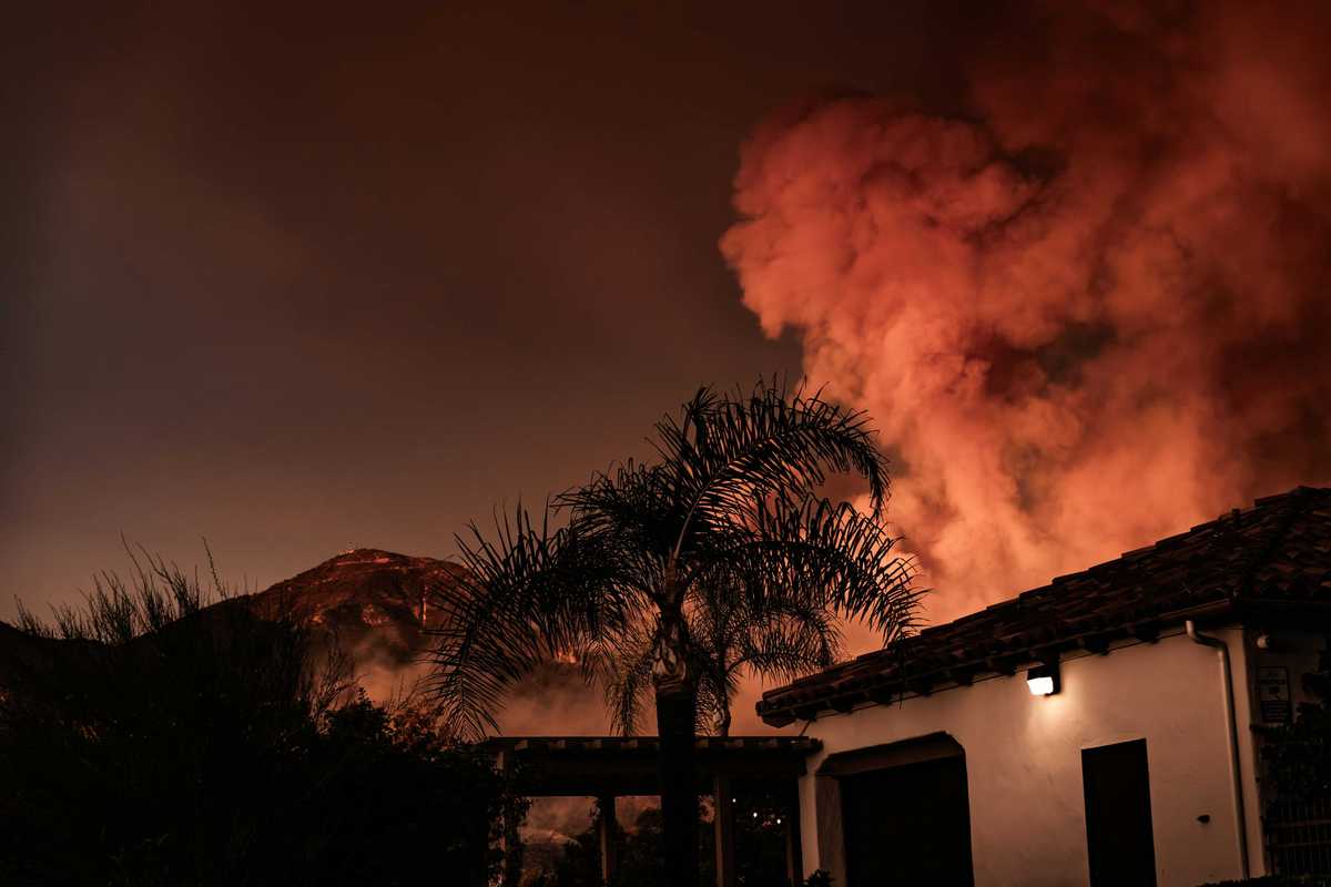 A large plume of smoke billowing behind a building