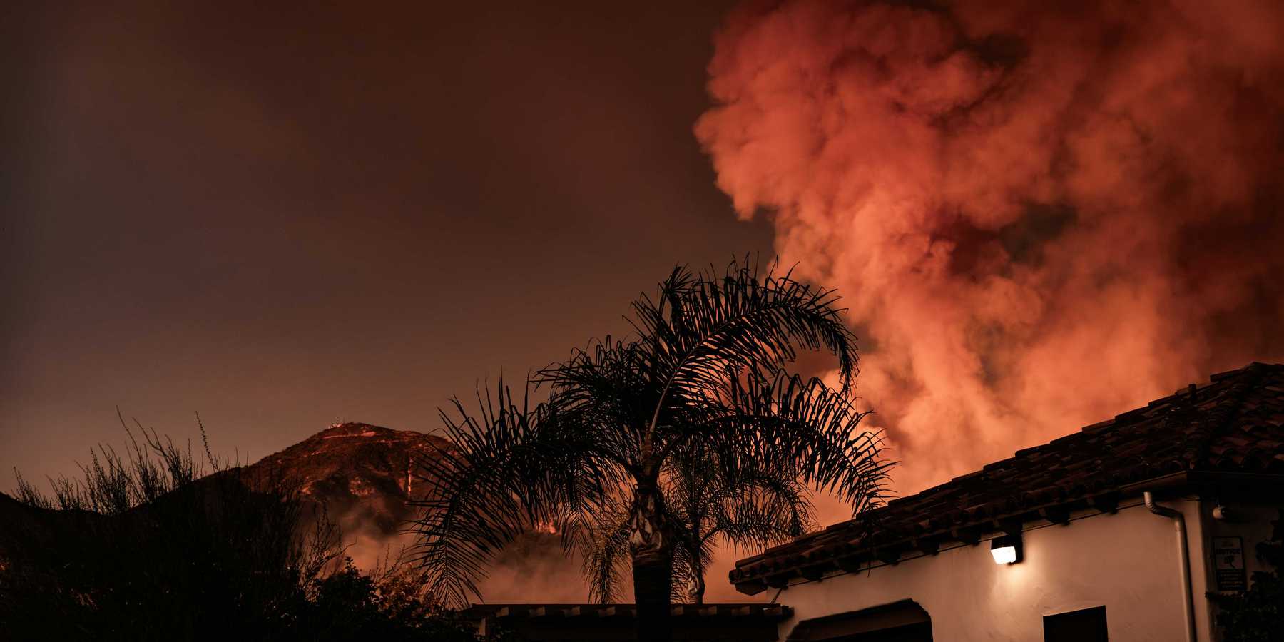 A large plume of smoke billowing behind a building