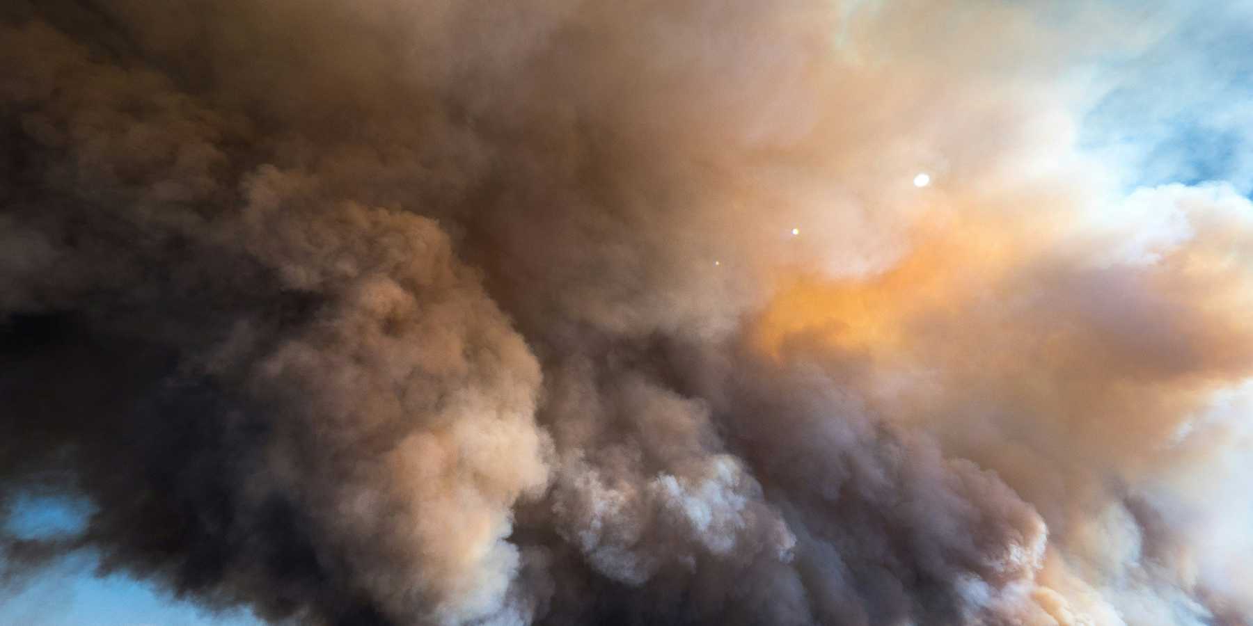 A large plume of smoke from a wildfire billows into the sky.