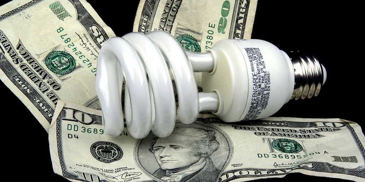 A lightbulb sitting on top of U.S. bills