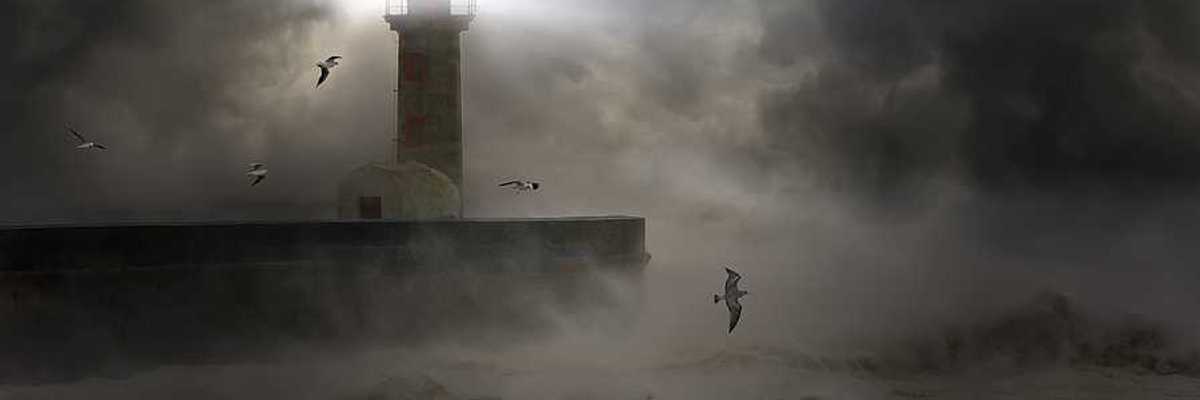 A lighthouse at the end of a promontory during a strong storm