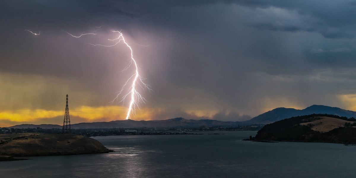 a lightning bolt is seen over a body of water.
